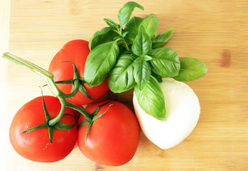Tomatoes mozarella and basil salad ingredients on wooden board top view
