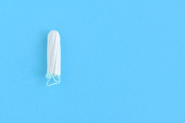 Soft cotton tampon for women period days with selective focus on blue background. Hygiene products for women's monthly menstruation. White protection tampons for female health care. Copy space