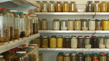 Shop raw materials without packaging, healthy nutrition wide assortment of cereals, legumes, dried fruits in jars and glass bottles on their own bags, store reusing recycling bags