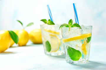 two glasses of lemonade with fresh lemon on turquoise background