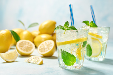 two glasses of lemonade with fresh lemon on turquoise background