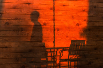 Abstract shadow of human on the wooden wall texture background in sunset .