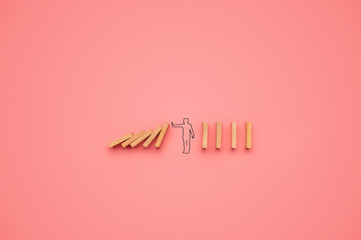 Shape of a man stopping dominos from falling - obrazy, fototapety, plakaty