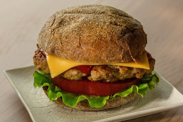 The rye bread burger with tomato, lettuce, fried meat  and cheese