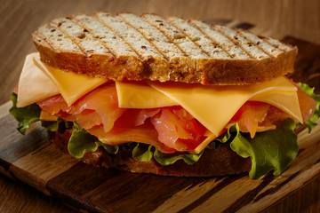 The sandwich with salmon, lettuce, tomato and cheese.