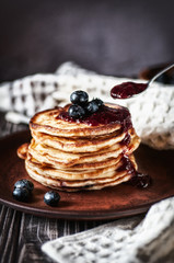 Pancakes with blueberry and honey. On a wooden table with a white towel