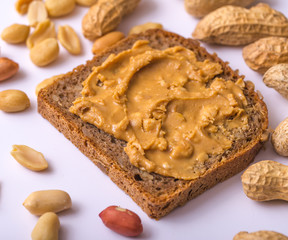 Bread spread with peanut butter on white napkin.