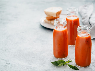 Delicious gaspacho soup in glass bottles. Traditional spanish cold soup puree gaspacho or gazpacho on gray cement background with copy space for text