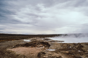 Endless Icelandic landscapes. Pale white geyser steam and clouds on the horizon