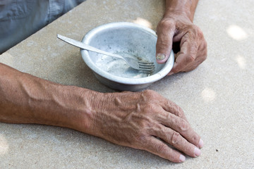 Hungry. Poor old man's hands an empty bowl. Selective focus. Poverty in retirement. Alms