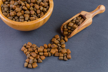 dog food in a wooden bowl with a scoop on black background