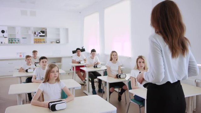 Amazing future computer science class in a schoo. Students listening to their teacher explaining how virtual reality headsets work.
