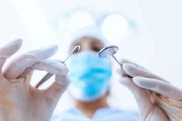 Dentista Odontoiatra con specchio e specillo mentre visita la bocca di un paziente. Visto sfuocato