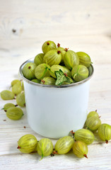 Set of organic gooseberry. Gooseberries fruits in a metal cup. Green gooseberry over rustic wooden background. Sweet and juicy berry. Top view.