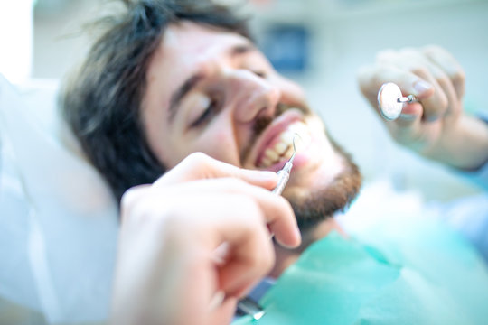 Paziente fa il dentista fai da te, curarsi i denti da solo con specchietto e specillo.