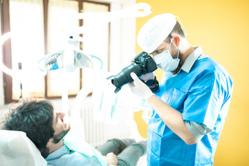 Fotografo odontoiatra per la fotografia della dentatura d un paziente sdraiato sulla poltrona.