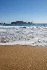 Sea wave at the beach low perspective shot with islands on the background
