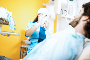 Giovane ragazza dentista odontoiatra da il cinque con la mano al paziente dopo l'operazione ai...