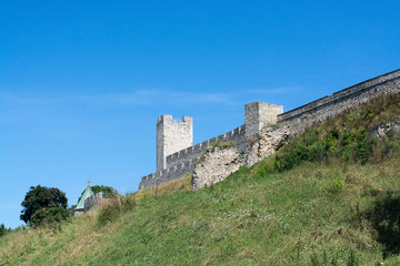 Fototapeta premium Kalemegdan fortress stone tower and fortification wall on a green park hill, against the clear blue sky, Belgrade, Serbia