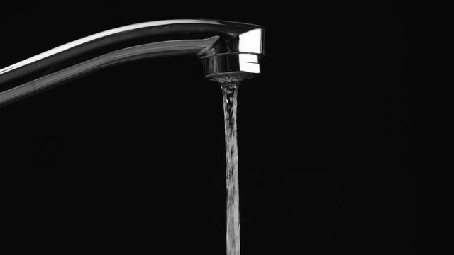 water flows from the tap on a black background, then the water stops