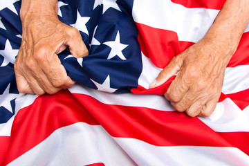 Fototapeta premium Elderly man hands compresses a USA flag.