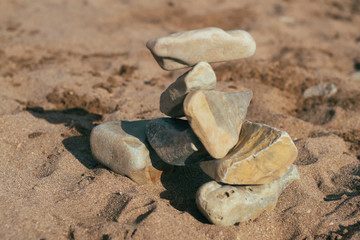 Fototapeta na wymiar stones lie on the stones. feng shui on the beach. Creating a balance in the sand