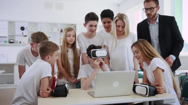 Futuristic modern school with techno education. Group of young students using a laptop and virtual reality exploring new things during a lesson.