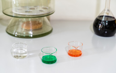 Colourful chemical liquid solutions in glass flasks on white laboratory worktop