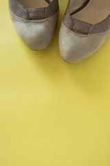 Elegant female shoes on yellow background, space for text. Flat lay, top view. Minimal fashion concept in pastel colored
