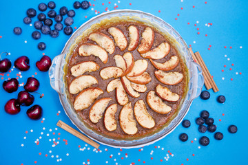 Tarta de manzana con canela sobre fondo azul decorado con estrellas blancas y rojas, arándanos y cerezas.
