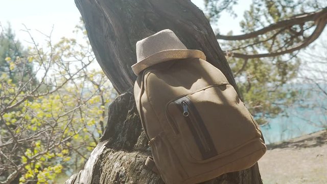 Packed camping backpack with straw hat outdoors - hiking eqipment details. Traveler hipster backpack and hat, ready for summer holidays trip, travel background with copy space.