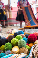 Spun and colored yarn in foreground with Quechuan women in background demonstrating process of...