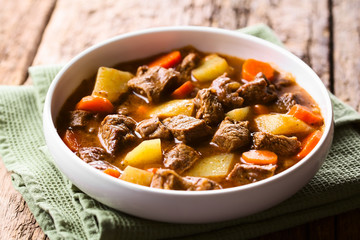 Fresh homemade beef stew with carrot and potatoes served in bowl (Selective Focus, Focus in the middle of the image) - obrazy, fototapety, plakaty