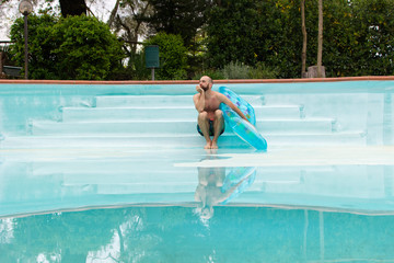 Naklejka premium Badegast mit einer Luftmatratze am leeren Schwimmbecken