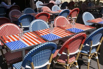 fun and colorful tables and chairs at a terrace in France wth the American flag 