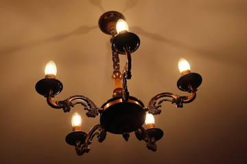 Fototapeta na wymiar Old chandelier with light candles on dark background.
