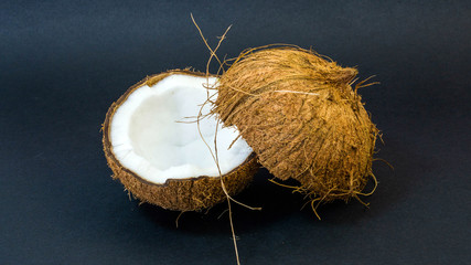 Coconut, exotic fruit, two halves of the fruit in the shell, dark background, selective focus, selective light, close-up