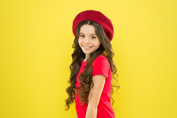 parisian child on yellow background. summer fashion and beauty. happy girl with long curly hair in beret. little girl in french style hat. childhood. hairdresser salon. happy girl in summer