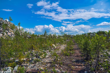 Mountain slope with large stones against a blue summer sky with white cumulus clouds.