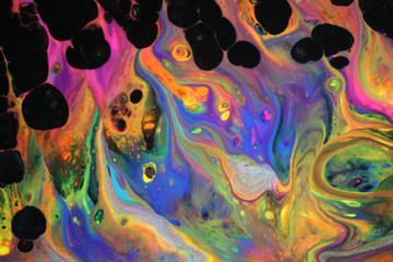 Abstract acrylic pour painting in vibrant retro neon colors and black cells popping up which...