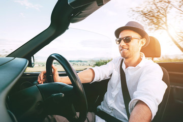 Smiling Man driving cabriolet car by province mountain road inside car view