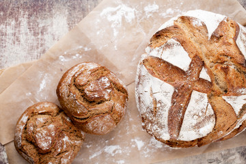 Gold rustic crusty loaves of bread and buns on wooden background. Still life captured from above top view, flat lay.