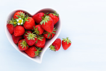 Strawberry heart. Fresh strawberries in plate on white wooden table. Top view, copy space.
