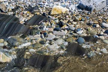 pebble stones on the sea beach, the rolling waves of the sea with foam
