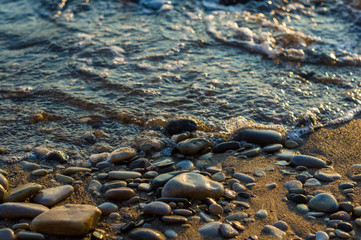 pebble stones on the sea beach, the rolling waves of the sea with foam
