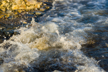 pebble stones on the sea beach, the rolling waves of the sea with foam