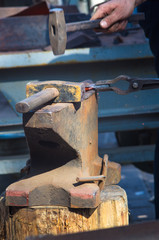 blacksmith performs the forging of hot glowing metal on the anvil