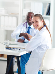 Obraz premium Two happy smiling young medical people handshaking at office. Doctors. Teamwork