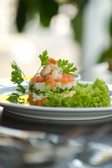 Olivier salad with shrimps, eggs and vegetables on a white plate. Depth of field