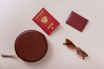Female minimum travel set. Maroon passport, cardholder and wallet with a bag and glasses on a...